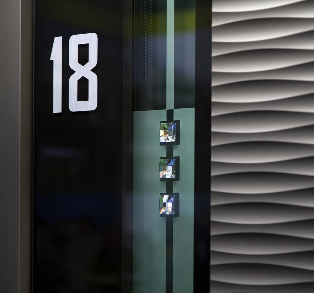 Personalizirani dodatki na vhodnih vratih: bela hišna številka 18 in kristali Swarovski.