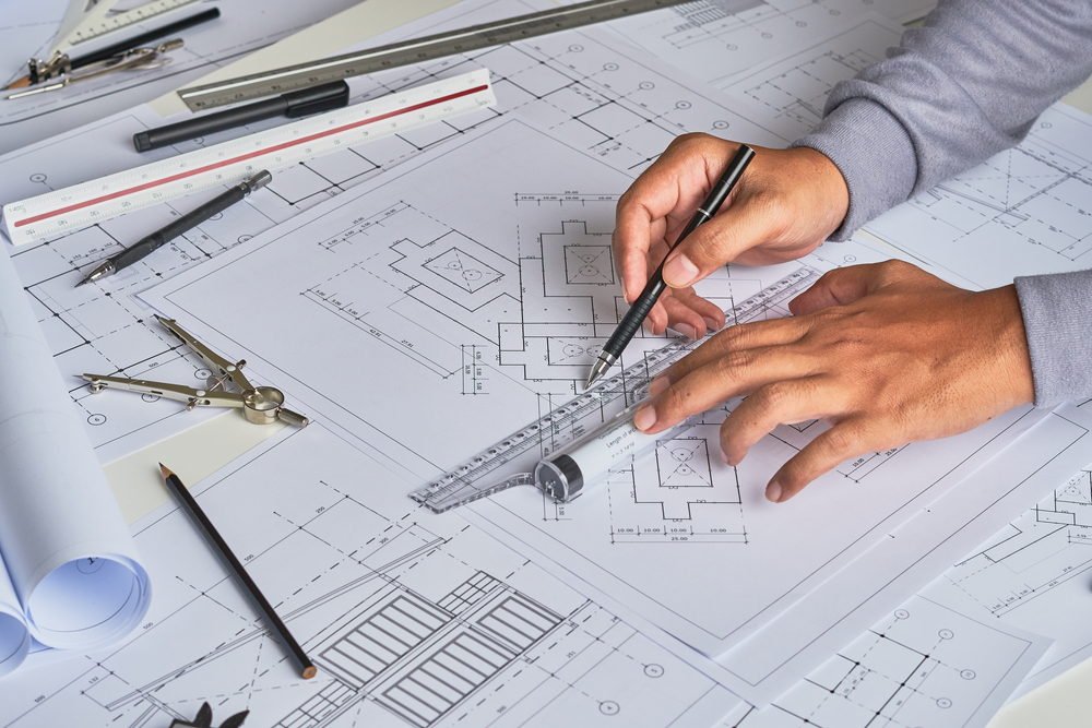 Ein Architekt verwendet einen Bleistift und ein Lineal, um einen Grundriss für ein zukünftiges Haus zu zeichnen.