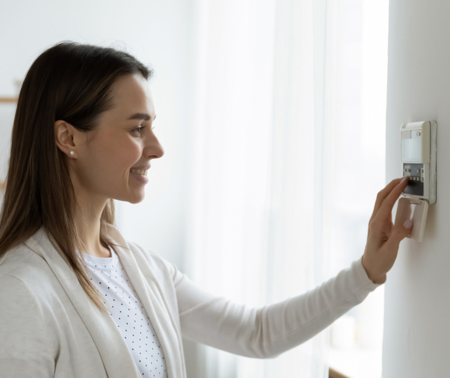 Ženska v dnevni sobi uravnava temperaturo in vlažnost zraka s pomočjo stenskega pripomočka.