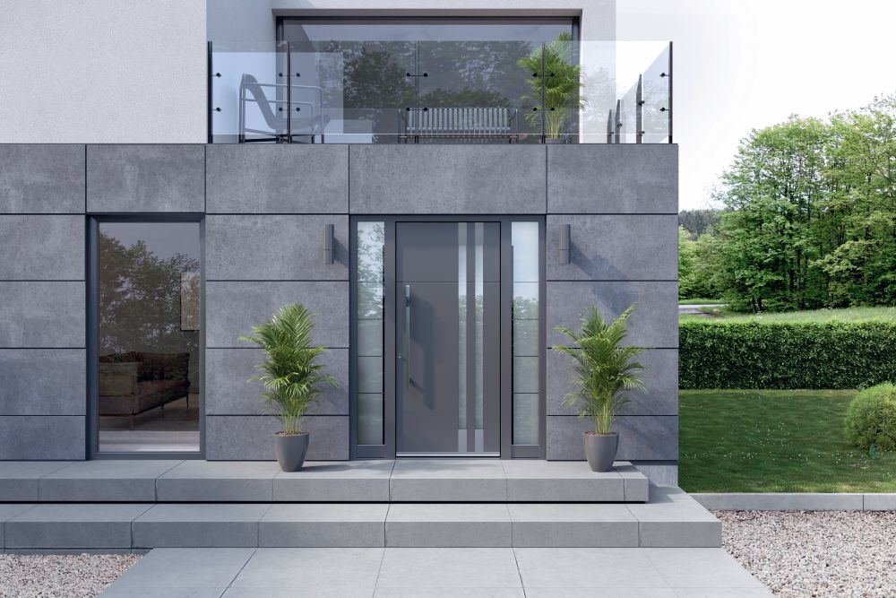 Siva fasada hiše s sivimi vhodnimi vrati z obsvetlobo