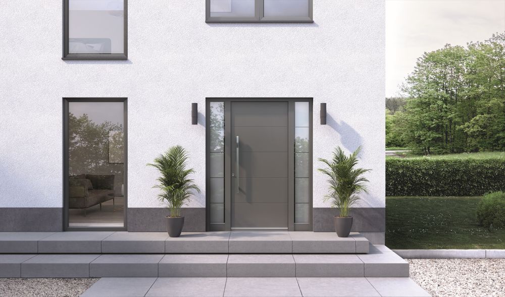 Bela fasada hiše s sivim coklom ter sivimi vhodnimi vrati