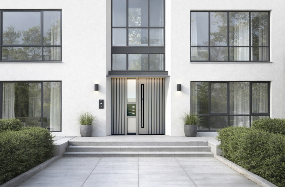 Večstanovanjska stavba z veliko steklenimi površinami in sivimi vhodnimi vrati