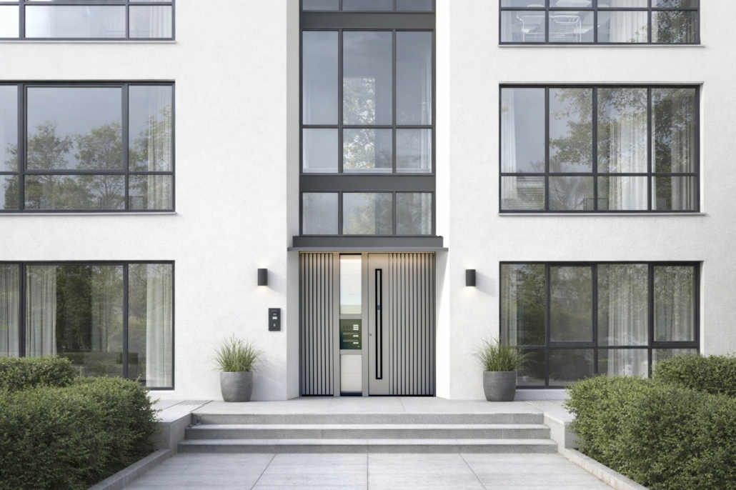 Večstanovanjska stavba z veliko steklenimi površinami in sivimi vhodnimi vrati