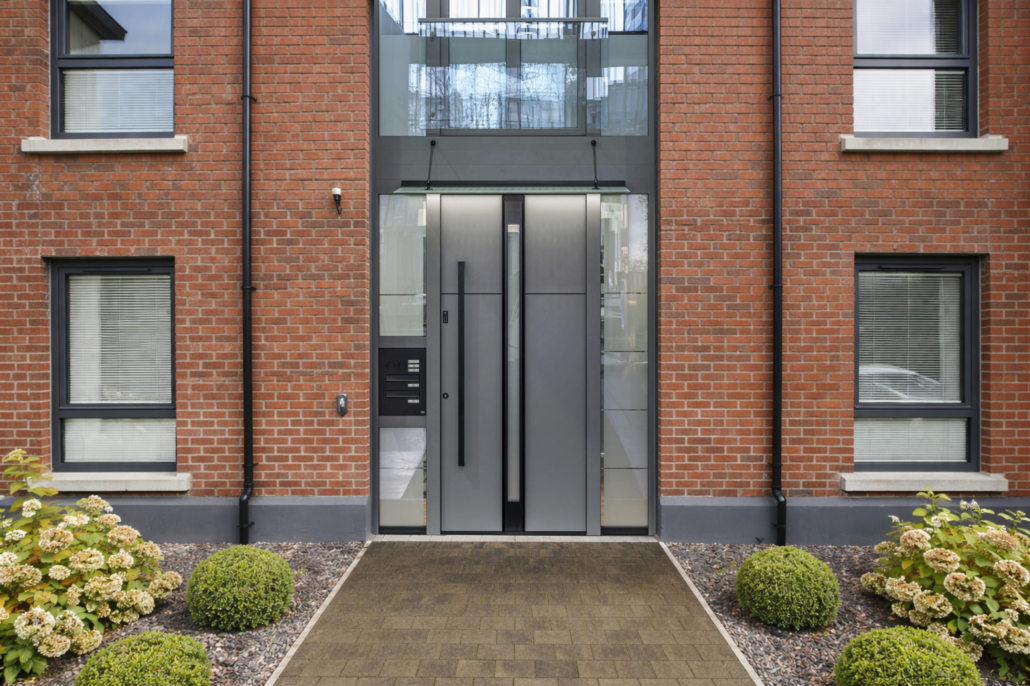 Siva vhodna vrata s poštnim nabiralnikom na bloku rdeče opečnate fasade